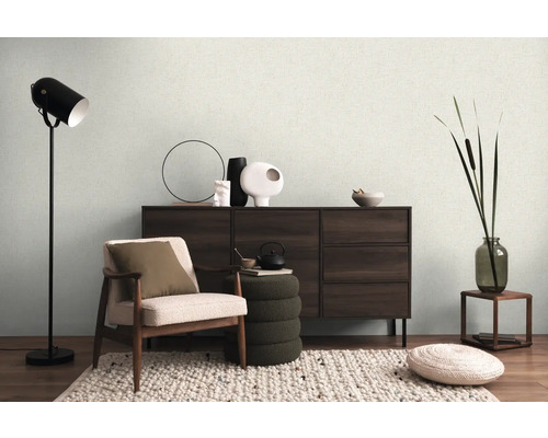 Obývacia izba s kreslom, komodou, stojacou lampou a dekoráciami pre útulnú atmosféru.