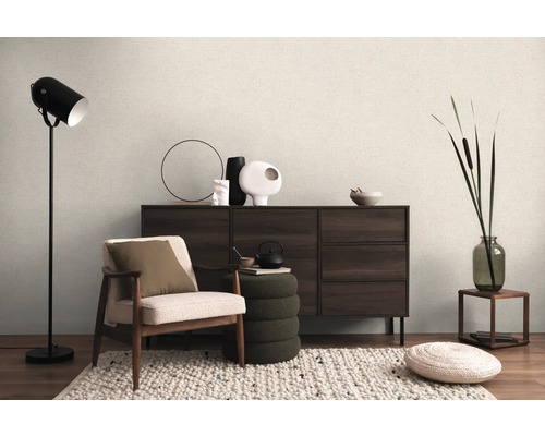 Interiér s kreslom, stojacou lampou, komodou a dekoratívnymi prvkami pre útulnú atmosféru bývania.