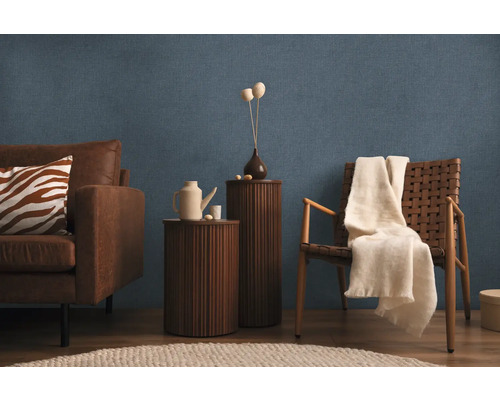 Obývacia izba s pohovkou, kreslom, príručnými stolíkmi a dekoráciami na modrej štruktúrovanej tapete