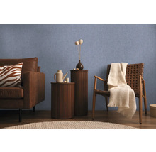 Obývacia izba s pohovkou, kreslom a odkladacími stolíkmi pred modrou stenou