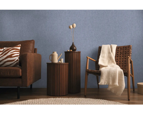 Obývacia izba s pohovkou, kreslom a odkladacími stolíkmi pred modrou stenou