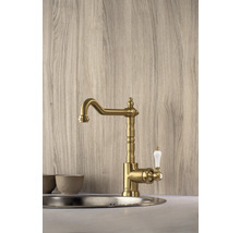 Zlatá kuchynská batéria s bielou rukoväťou namontovaná v umývadle