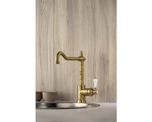 Zlatá kuchynská batéria s bielou rukoväťou namontovaná v umývadle