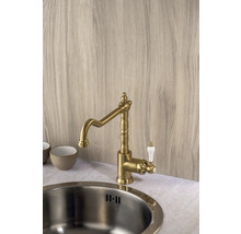 Mosadzná kuchynská batéria s bielou rukoväťou vedľa drezu