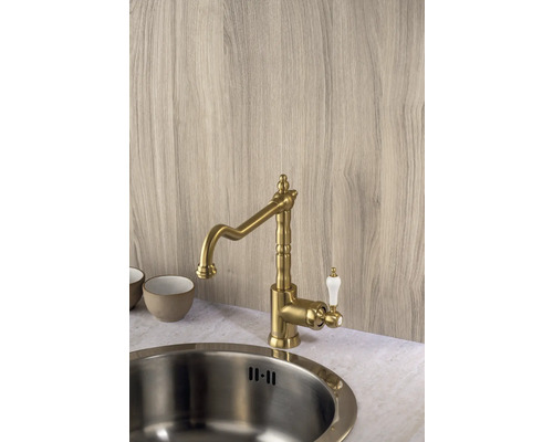 Mosadzná kuchynská batéria s bielou rukoväťou vedľa drezu