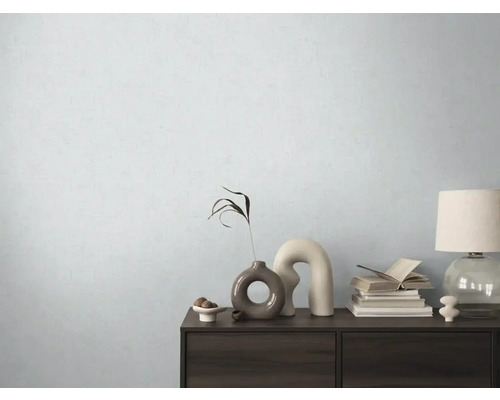 Dekoratívna komoda s vázami, knihami a lampou pred svetlou stenou