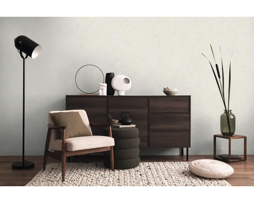 Obývacia izba s kreslom, komodou, stojacou lampou a dekoráciou pre útulnú atmosféru.