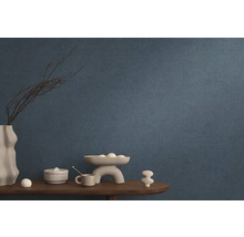 Modrá vliesová tapeta v obývacej izbe s dekoráciou na drevenom stole.