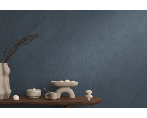 Modrá vliesová tapeta v obývacej izbe s dekoráciou na drevenom stole.