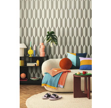 Obývacia izba s geometrickou tapetou, pohovkou, odkladacím stolíkom a dekoratívnymi doplnkami pre štýlový interiér.