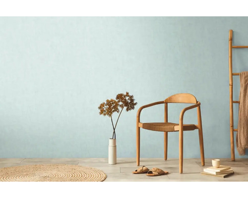 Svetlá miestnosť so stoličkou, vázou, dekoráciou a okrúhlym kobercom pre útulnú atmosféru.