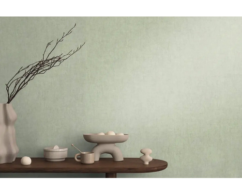 Dekoratívna scéna s vázou, konármi a rôznymi predmetmi na stole pred stenou