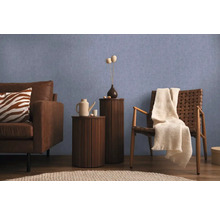 Obývacia izba s pohovkou, stoličkou a príručnými stolíkmi pred modrou stenou