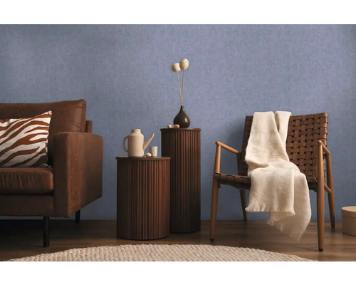 Obývacia izba s pohovkou, stoličkou a príručnými stolíkmi pred modrou stenou