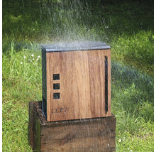 Drevená záhradná sprcha na drevenom podstavci, zavlažovaná na trávniku