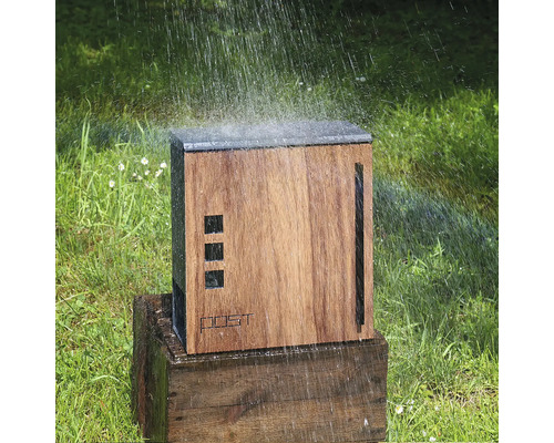 Drevená záhradná sprcha na drevenom podstavci, zavlažovaná na trávniku