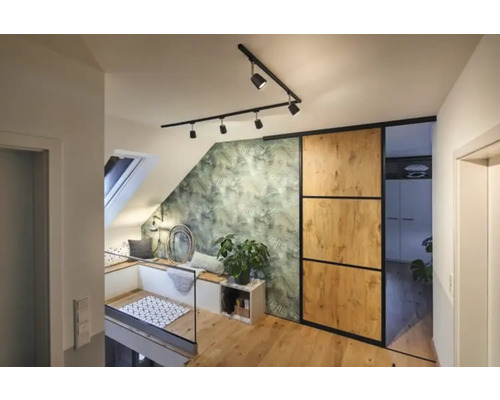 Svetlý podkrovný byt so strešným oknom, posedením, zelenou tapetou s motívom listov, posuvnými dverami a drevenou podlahou.