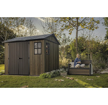 Záhradná scéna s dreveným záhradným domčekom a osobou sediacou na záhradnej lavičke