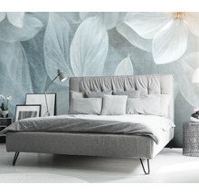 Spálňa s posteľou, nočným stolíkom a dekoratívnym kvetinovým motívom na stene.