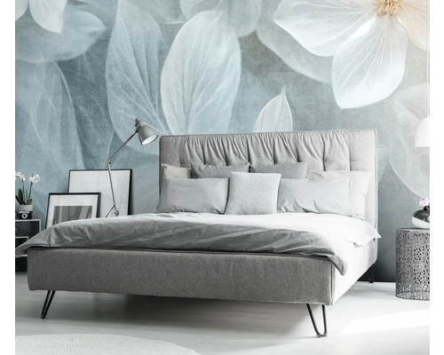 Spálňa s posteľou, nočným stolíkom a dekoratívnym kvetinovým motívom na stene.