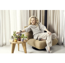 Žena sedí v kresle vedľa odkladacieho stolíka s rôznymi kaktusmi a sukulentmi v ozdobných kvetináčoch.