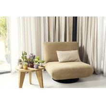 Kreslo s vankúšom vedľa stola s črepníkovými rastlinami pred závesmi