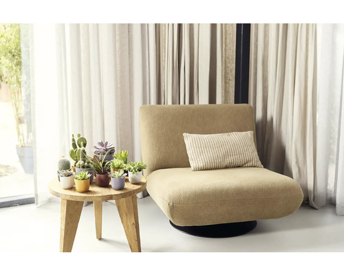 Kreslo s vankúšom vedľa stola s črepníkovými rastlinami pred závesmi