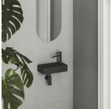 Moderná kúpeľňa s malým obdĺžnikovým umývadlom a oválnym zrkadlom