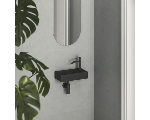 Moderná kúpeľňa s malým obdĺžnikovým umývadlom a oválnym zrkadlom