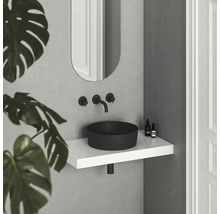 Moderná kúpeľňa s čiernym umývadlom na dosku, bielou policou a oválnym zrkadlom