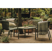 Záhradná scéna so stolom, stoličkami, vankúšom a dekou na terase obklopenej rastlinami