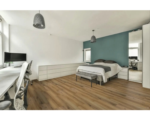 Svetlá spálňa s pracovným priestorom, posteľou, komodou a drevenou podlahou.