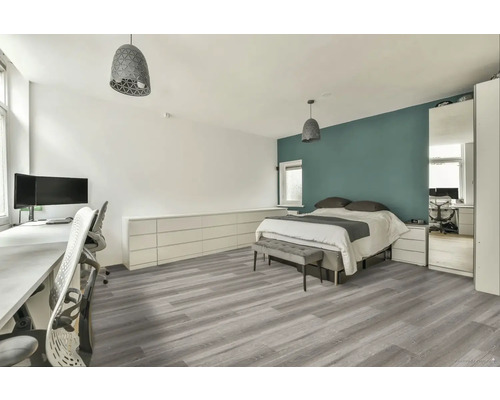 Svetlá spálňa s pracovným priestorom, posteľou, sivou podlahou a zodpovedajúcim osvetlením