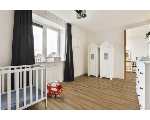 Svetlá detská izba s detskou postieľkou, drevenou podlahou a dvoma bielymi skriňami v tvare domu