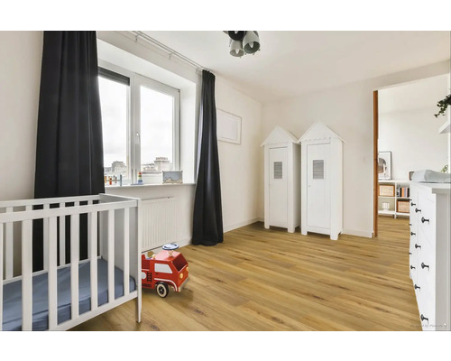 Svetlá detská izba s detskou postieľkou, drevenou podlahou a dvoma bielymi skriňami v štýle plážového domu.