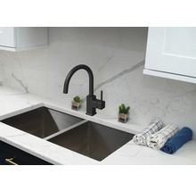 Kuchynský drez s vodovodnou batériou a dekoratívnymi prvkami na pracovnej doske.