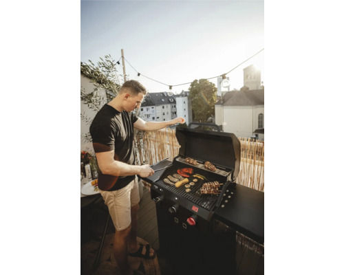 Muž griluje zeleninu a mäso na plynovom grile na balkóne.