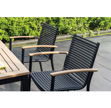 Dve záhradné stoličky s drevenými podrúčkami a čiernymi kovovými rámami stoja vedľa záhradného stola.