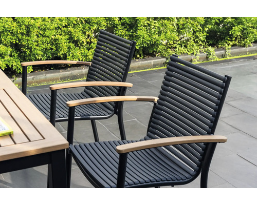 Dve záhradné stoličky s drevenými podrúčkami a čiernymi kovovými rámami stoja vedľa záhradného stola.