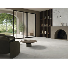 Svetlá obývacia izba s dlažbou, kreslom, konferenčným stolíkom a regálom