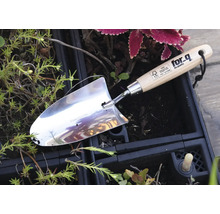 Nerezová jamkovač s drevenou rukoväťou v záhradnom záhone