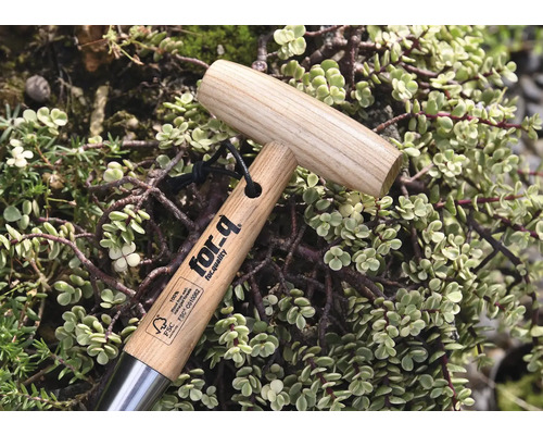 Záhradné náradie s drevenou rukoväťou a logom for-q, obklopené rastlinami