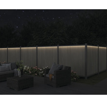 Záhrada s osvetleným plotom, posedením a kvetmi v noci