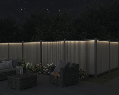 Záhrada s osvetleným plotom, posedením a kvetmi v noci