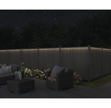 Osvetlený záhradný plot so záhradným nábytkom v noci