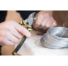 Osoba strihá drôt pomocou bočných štiepacích klieští značky Stanley.