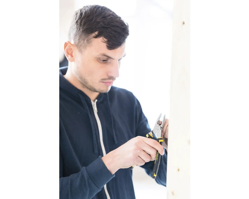 Muž pracuje s odizolovacími kliešťami Stanley na drevenom ráme