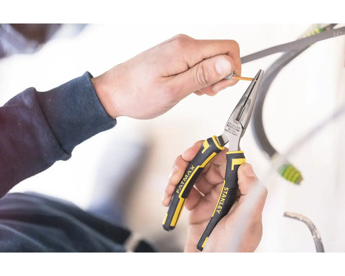 Ruky používajú úzke kliešte Stanley Fatmax na zvliekanie kábla.