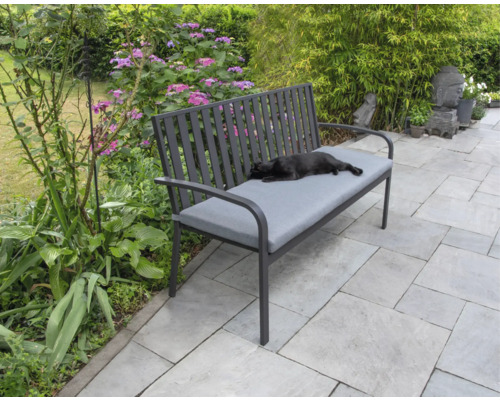 Záhradná lavica so sivou podložkou a ležiacou mačkou v záhrade.