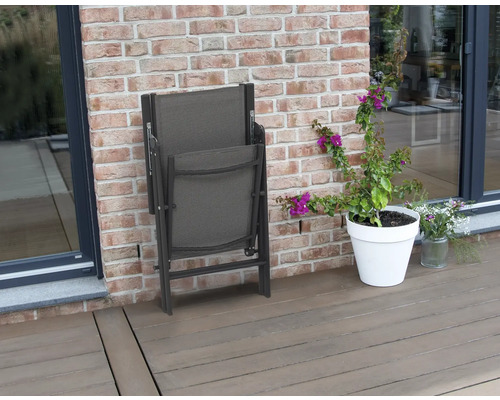 Skladacia záhradná stolička vedľa kvetináča na terase